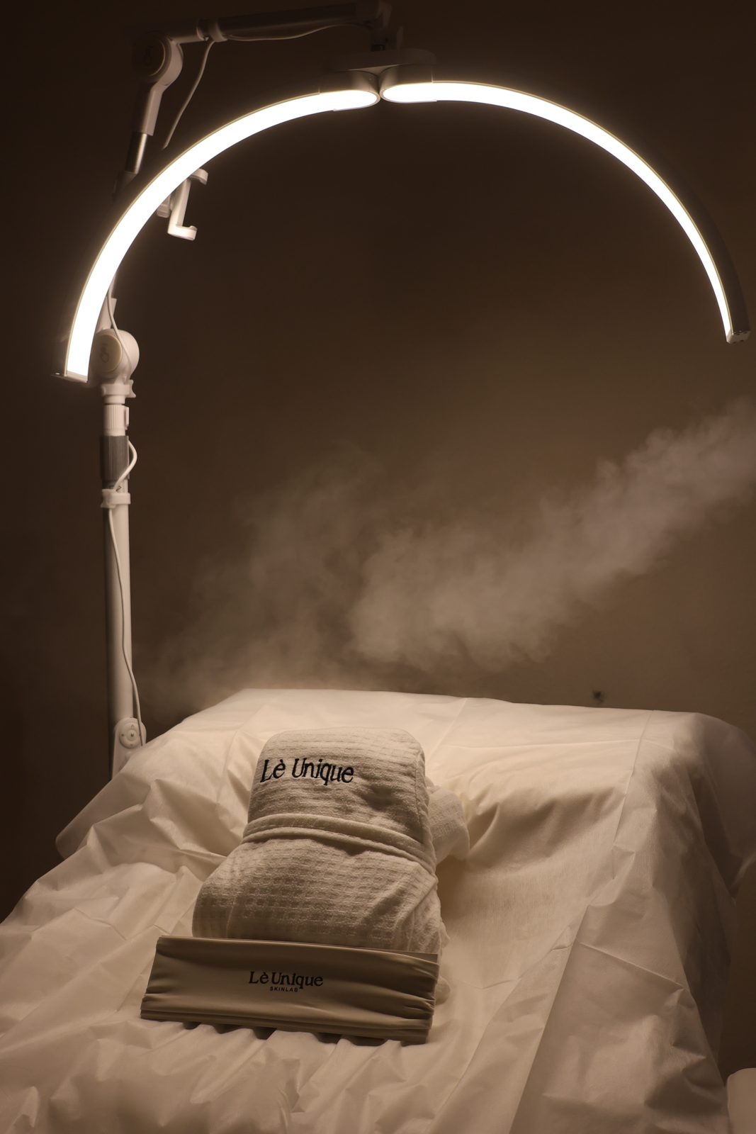 Folded branded towels and robe in a Lè Unique Skinlab treatment room