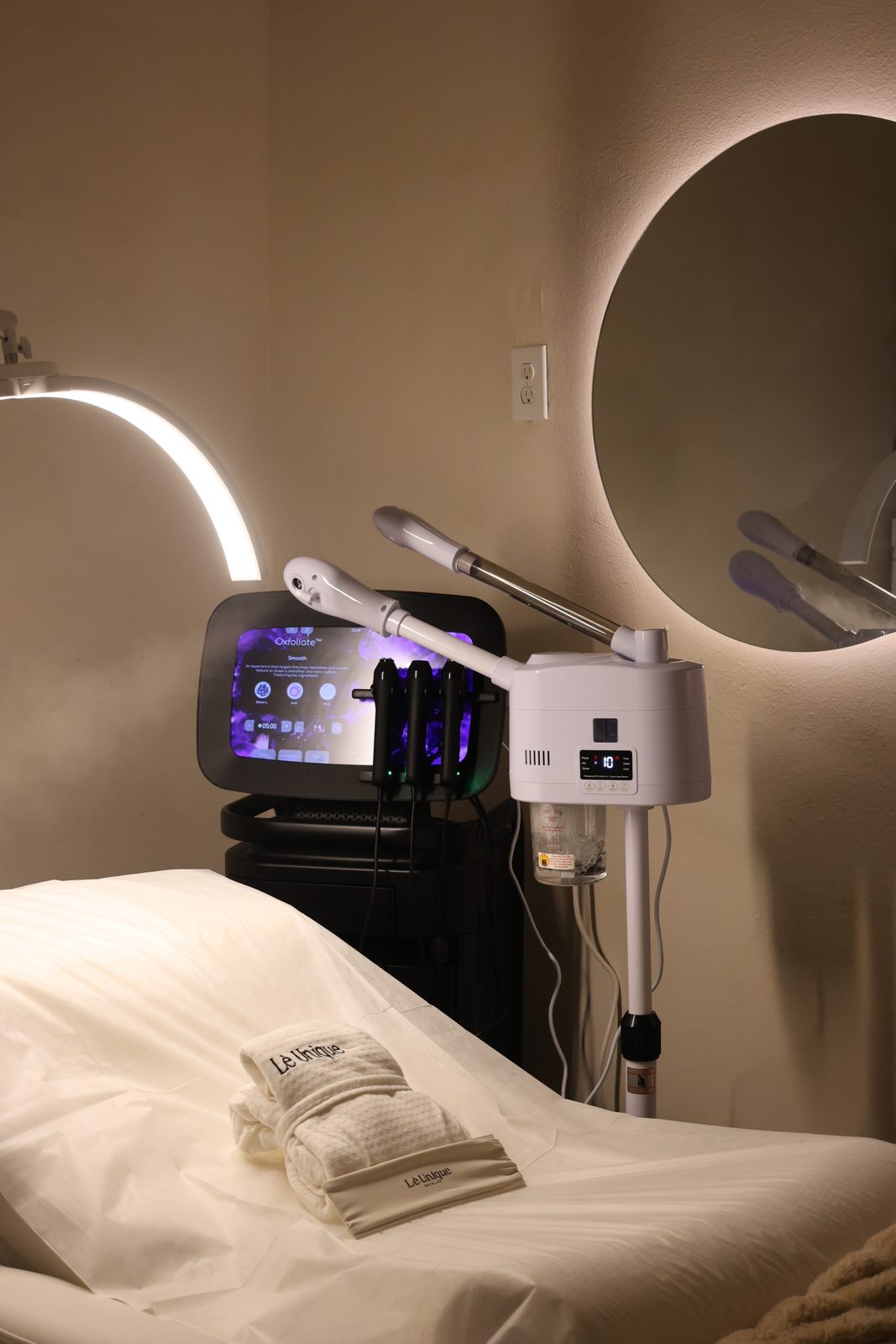 Treatment room bed with towels and equipment at Lè Unique Skinlab